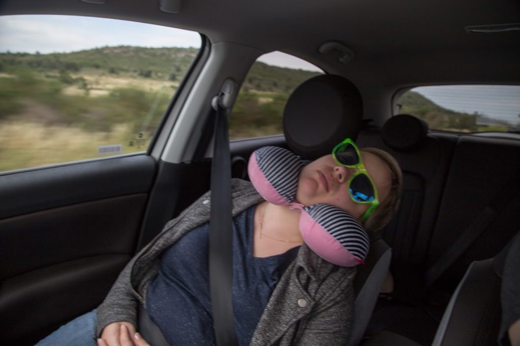 Sleeping in the front seat of the car, sunglasses on.