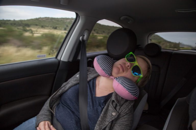 Sleeping in the front seat of the car, sunglasses on.
