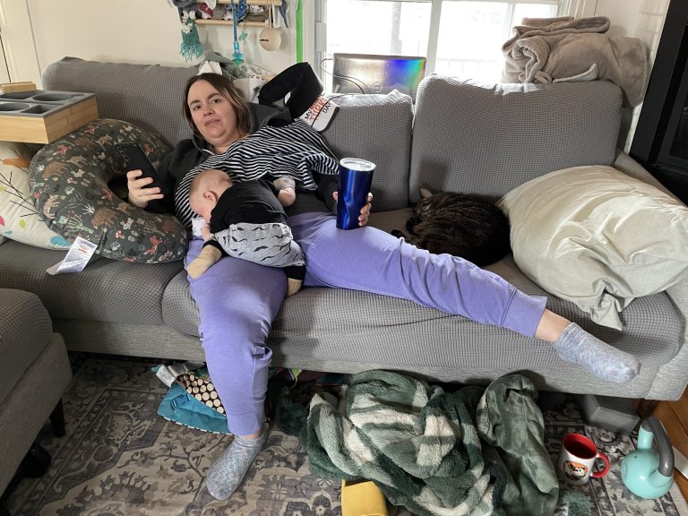 Postpartum doula logs data in her phone while baby naps.